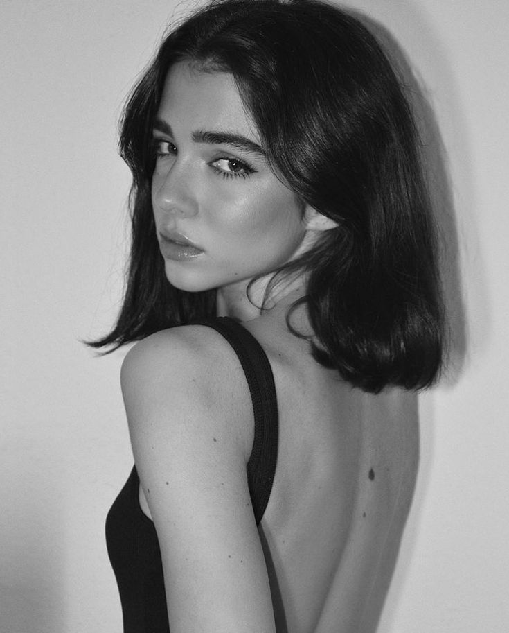 a black and white photo of a woman with her back to the camera, wearing a tank top