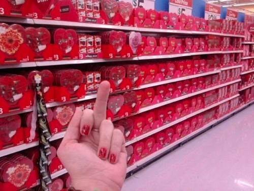 a woman is pointing at the red heart - shaped decorations on display in a store