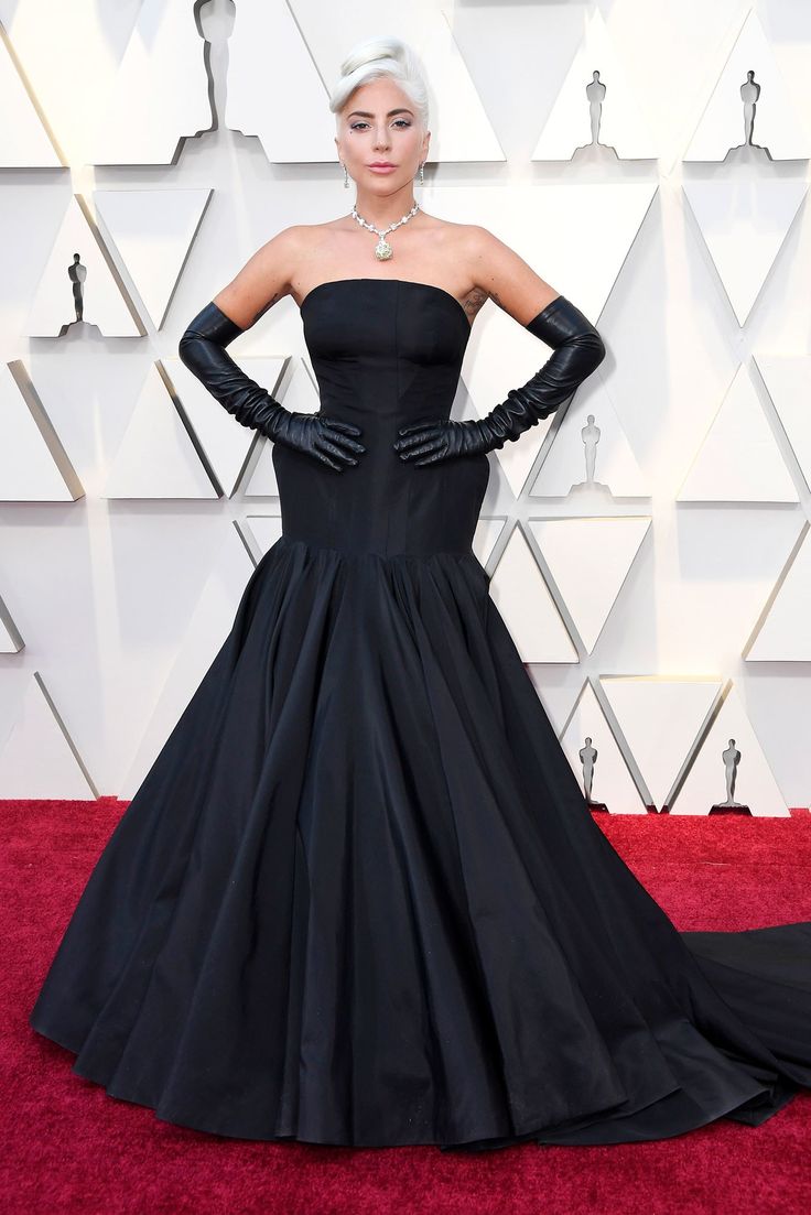 lady in black gown and gloves on red carpet at oscars awards ceremony, with one hand on her hips