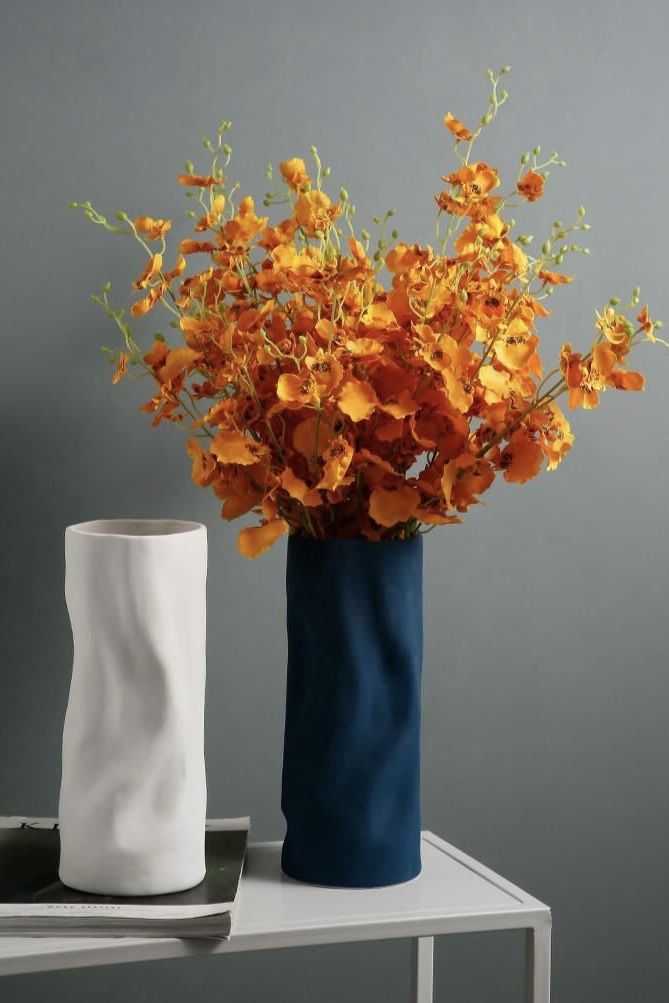 there are two vases with orange flowers in them