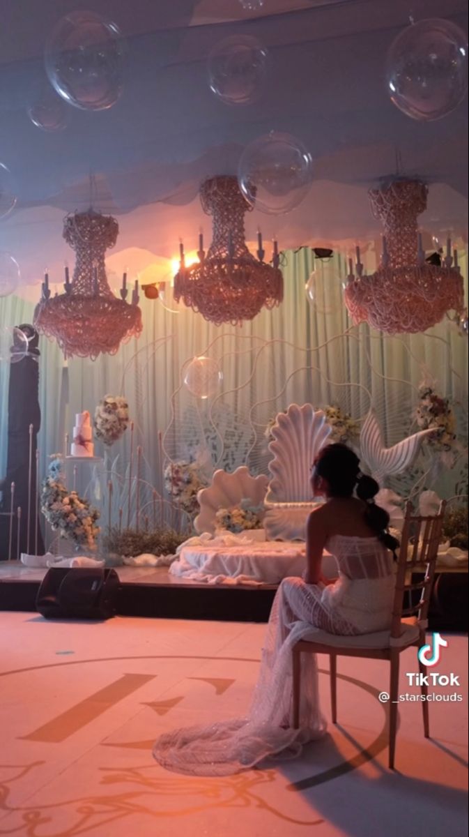 a woman sitting on a chair in front of a chandelier filled with bubbles