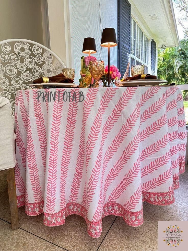 a pink and white table cloth on top of a chair next to a lamp shade