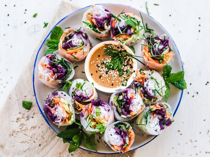 a white plate topped with rolls covered in sauce and garnished with veggies