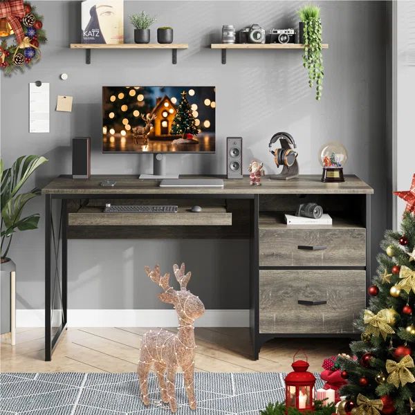 a christmas tree is in front of a desk with a computer monitor and deer figurine