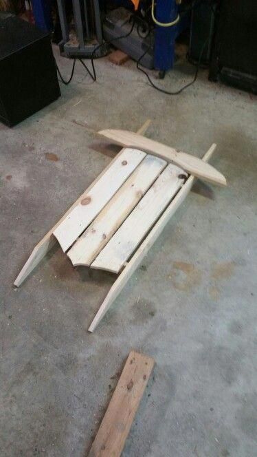 a wooden surfboard laying on the ground next to some wood planks and tools