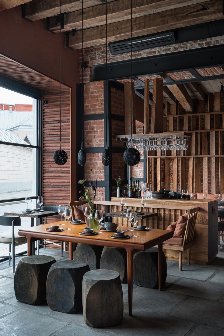 an industrial style dining room with brick walls and exposed ceilings, wooden tables and stools