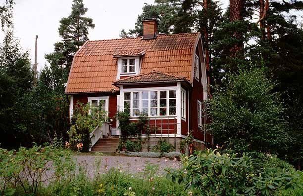 a red house surrounded by trees and bushes