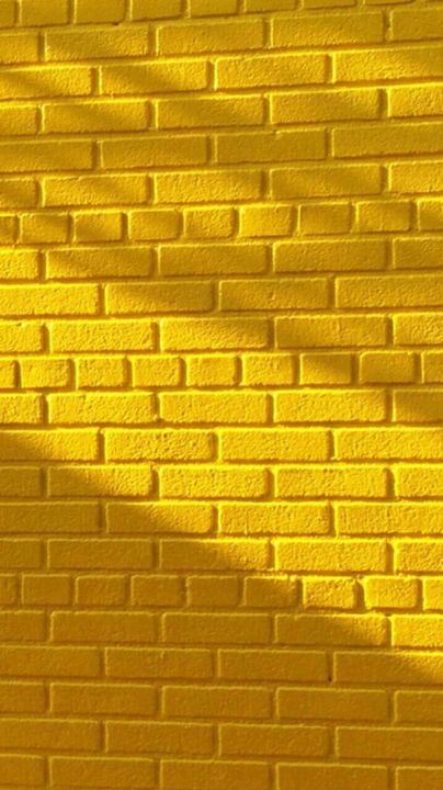 a yellow brick wall is shown with the shadow of a tree on it's side