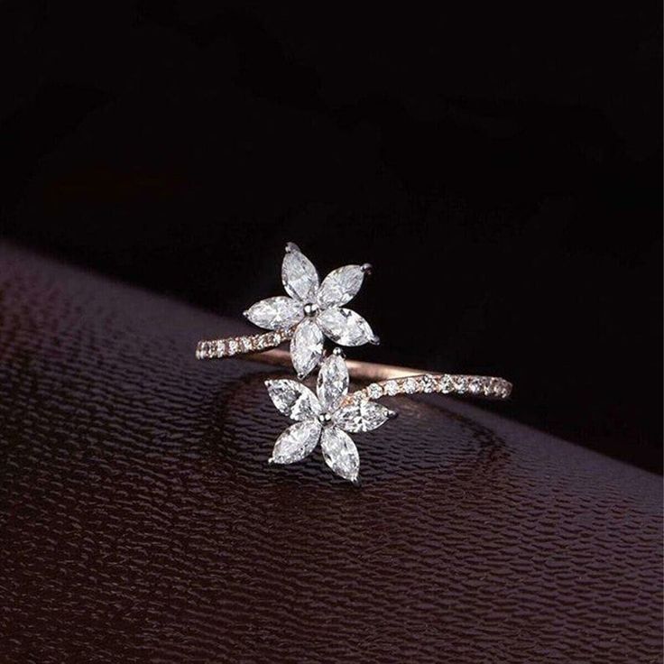 a diamond flower ring sitting on top of a table