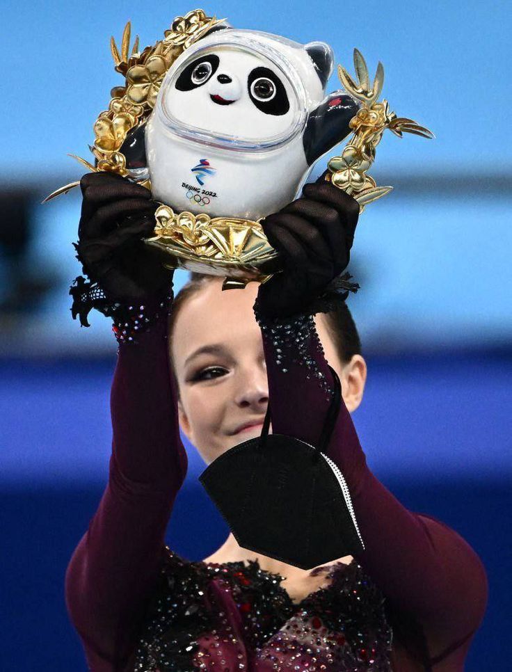 a woman holding up a stuffed panda bear on top of her head at the olympics