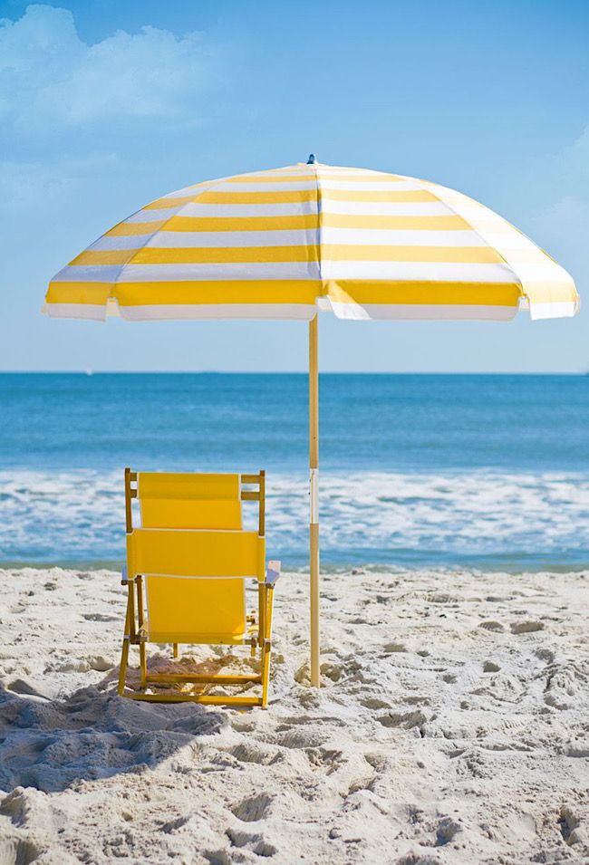 a yellow chair under an umbrella on the beach