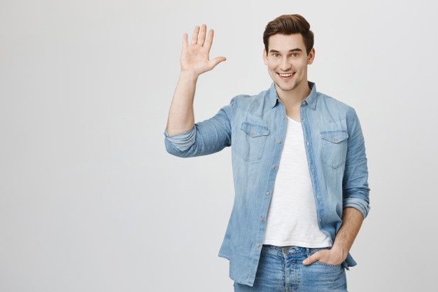 a young man is smiling and waving with his hand in the air while standing against a white background