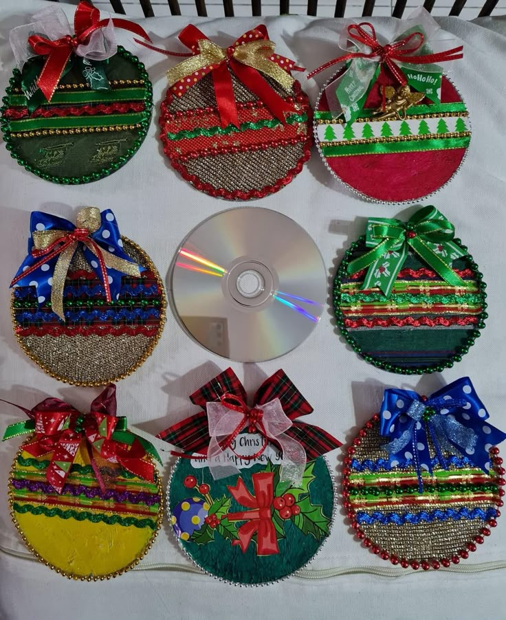 a cd sitting on top of a white table cloth covered in christmas themed ornaments with ribbons and bows