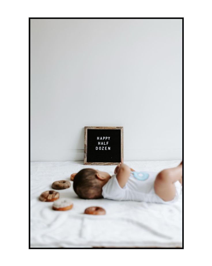 a baby laying on its back next to a sign that says happy birthday dyzen