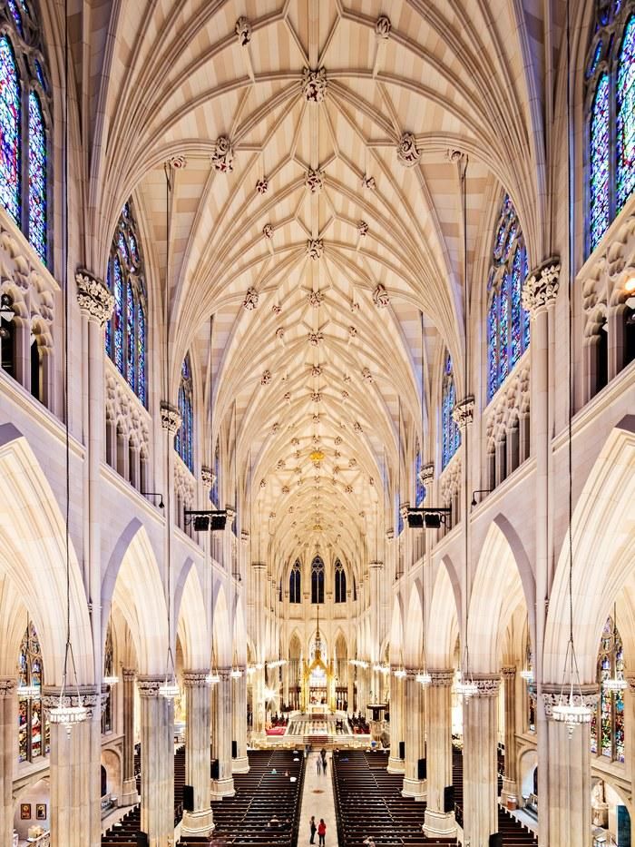 the interior of a large cathedral with pews and stained glass windows on both sides