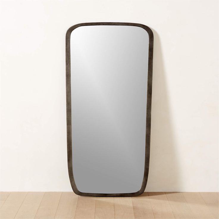 a large rectangular mirror sitting on top of a wooden floor next to a white wall