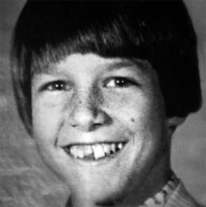 black and white photograph of a young boy with short hair wearing a shirt smiling at the camera