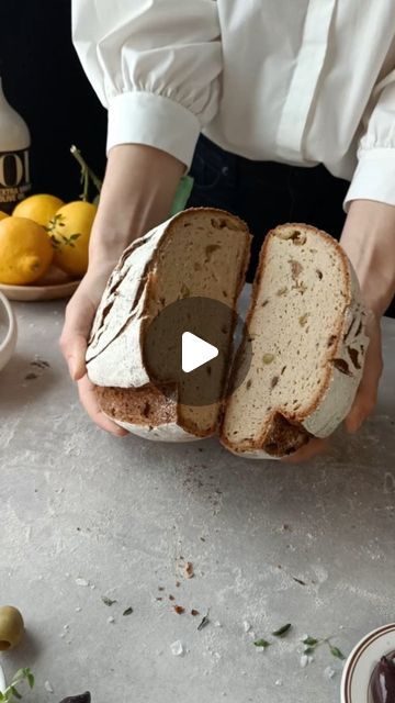 a person holding a loaf of bread on top of a table