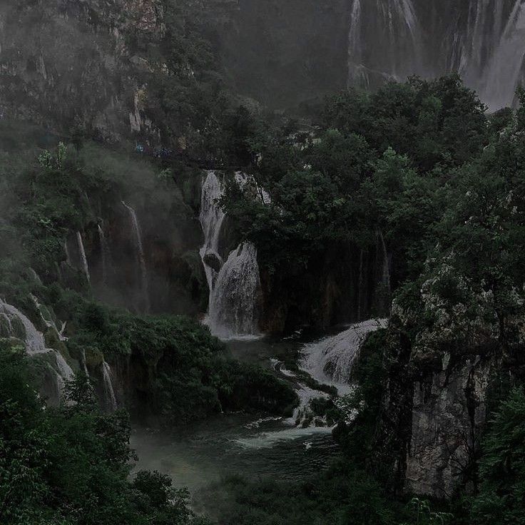 the waterfall is surrounded by trees and fog