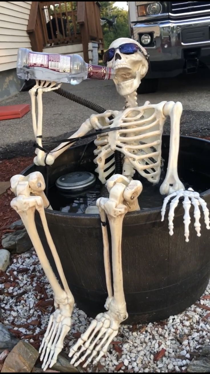 a skeleton sitting in a pot with a water bottle