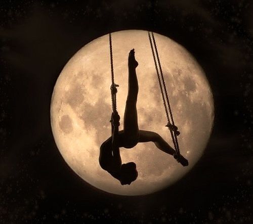 a person on a swing in front of the moon