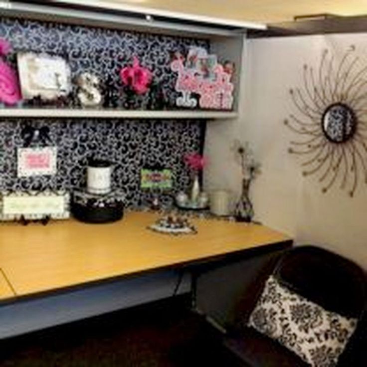 an office desk with black and white wallpaper, decorative items on the shelf above it