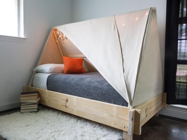 a bed with a tent on top of it in a room next to a window