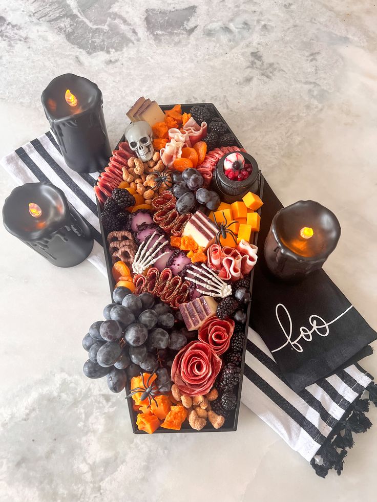 a table topped with candles and assorted food on top of black napkins next to each other