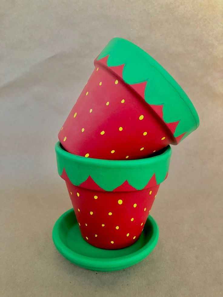 two plastic cups with strawberries on them sitting on a saucer and one has a green lid