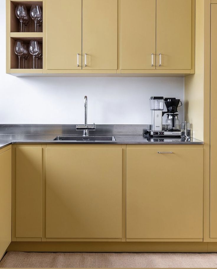 a kitchen with yellow cabinets and stainless steel counter tops, including a coffee maker in the center