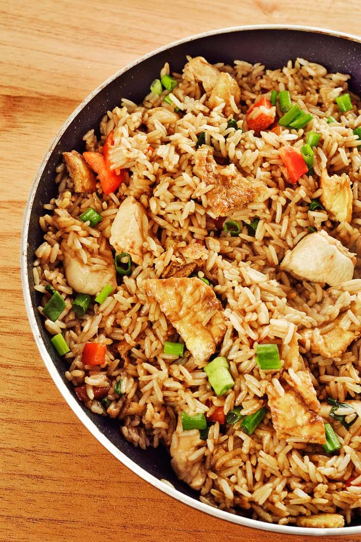 a pan filled with chicken and rice on top of a wooden table