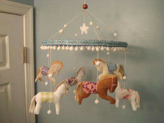 a baby crib mobile with horses hanging from it's sides in a room