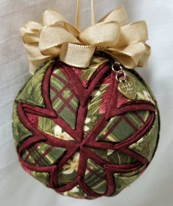 a christmas ornament hanging on a white table cloth with a ribbon and bow