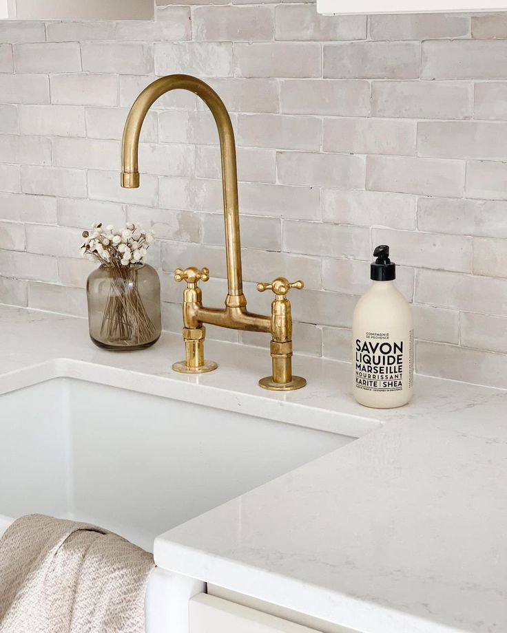 a white sink sitting under a faucet next to a counter top with soap