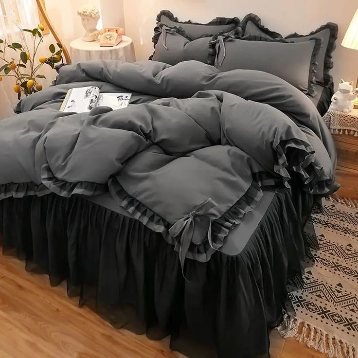 a bed with ruffled black sheets and pillows