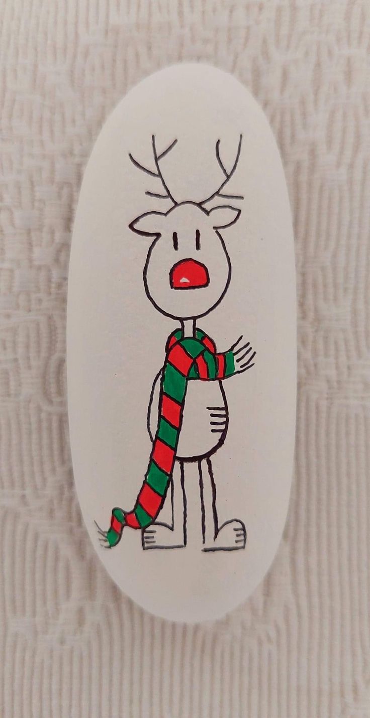 a white ceramic ornament with a drawing of a reindeer wearing a striped scarf