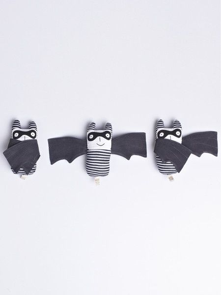 three stuffed bats hanging from the side of each other on a white wall with black and white stripes