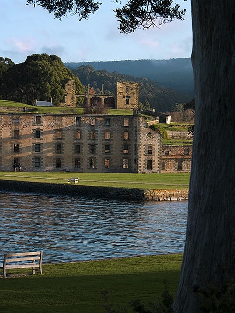 an old building sitting on top of a lush green field next to a lake in front of it