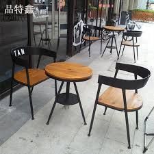 three wooden chairs and two black tables on the sidewalk