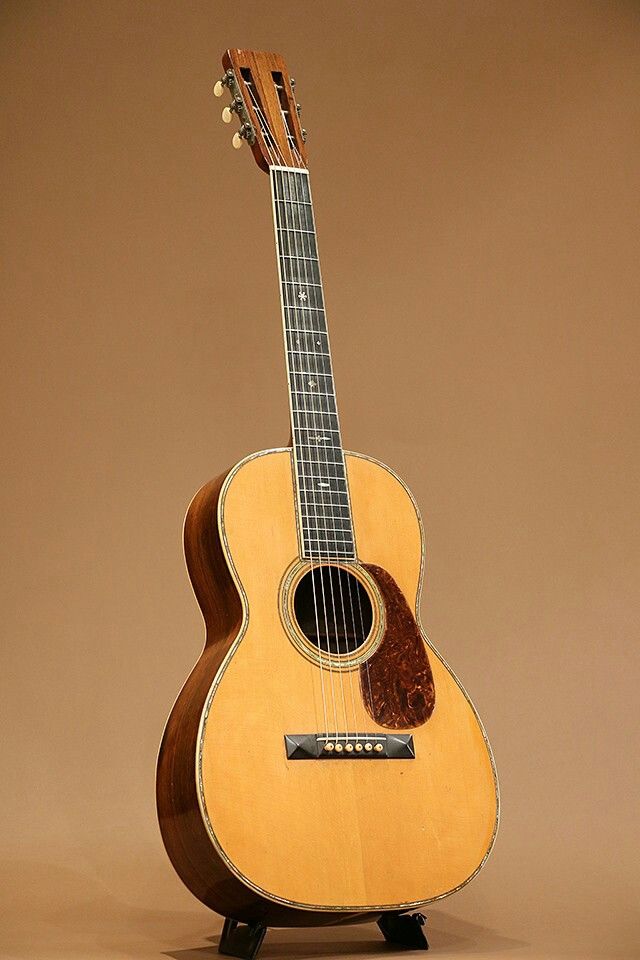 an acoustic guitar sitting on top of a wooden stand in front of a brown background