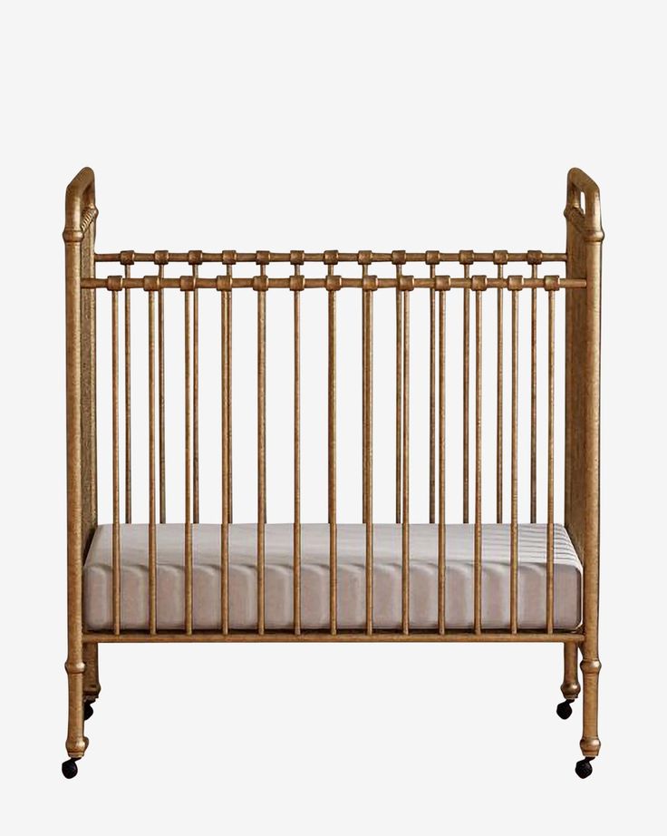 a baby crib with wheels on the side and a pillow in front of it