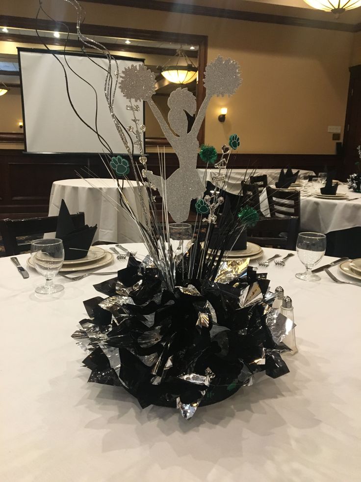 a centerpiece on top of a white table cloth covered table with silver and black decorations