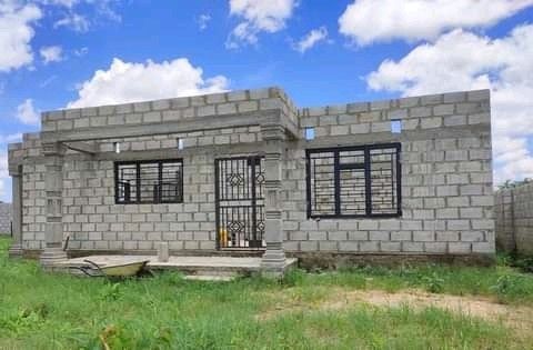 a small brick house sitting on top of a lush green field