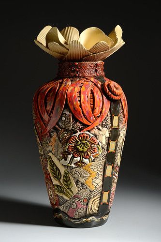 a decorative vase with an elaborate design on the top and bottom, sitting in front of a dark background