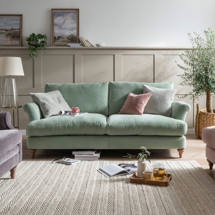 a living room scene with focus on the couch and chair, coffee table and potted plant