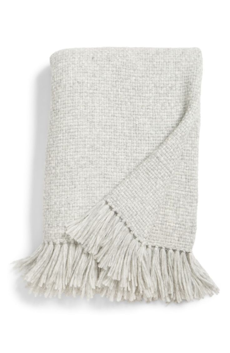 a white blanket with fringes on the bottom and one in grey, is shown