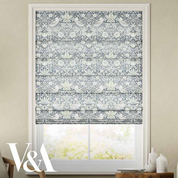 the roman blind in blue and white with an ornate pattern on it, next to a window