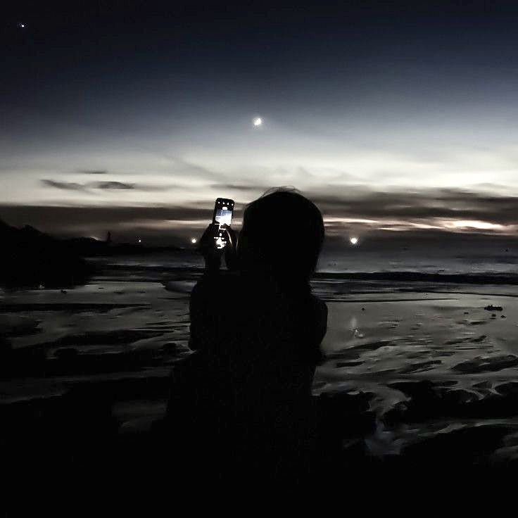 a person taking a photo at night on the beach