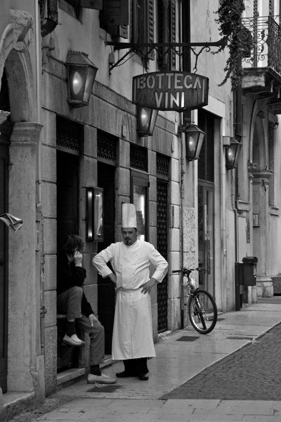 black and white photograph of a man standing in front of a wine shop