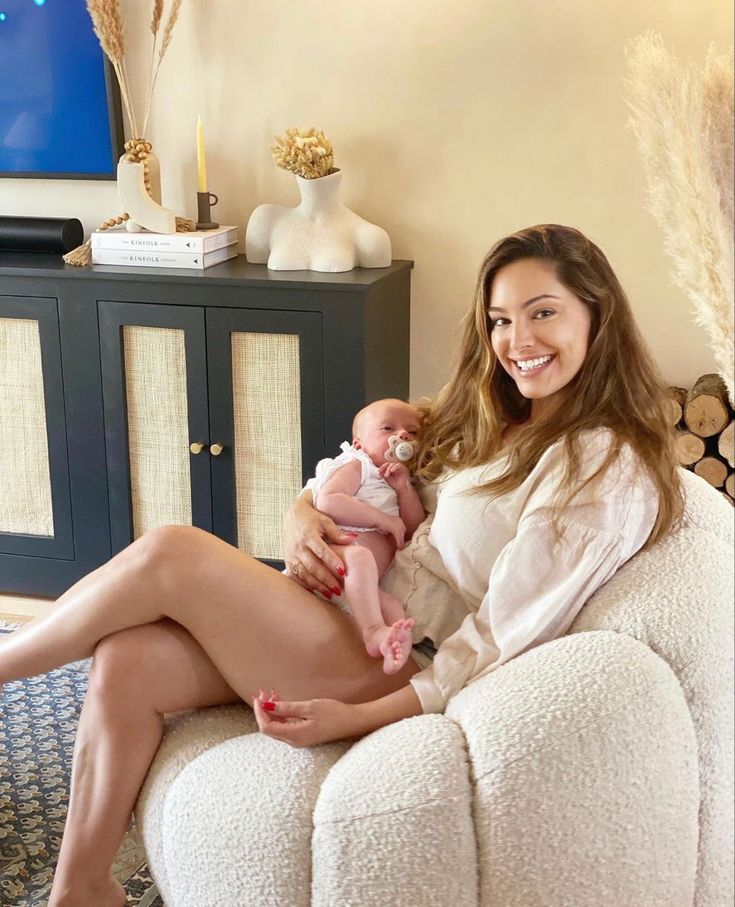 a woman sitting on a couch holding a baby